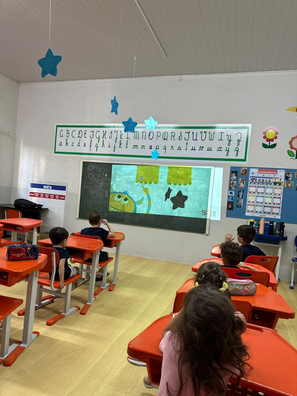 Sala de aula da Escola Aquarela – COC Jales com crianças atentas à projeção didática